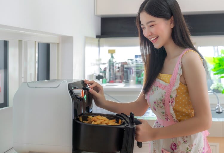 a woman in an apron putting food into a food processor