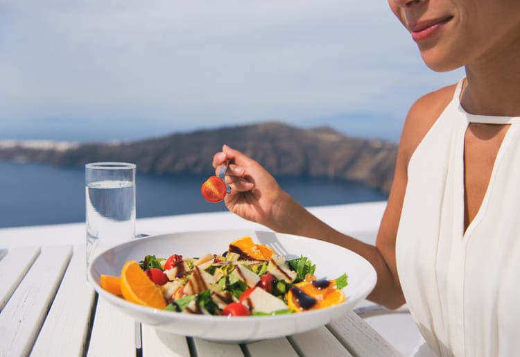 Woman enjoying a healthy salad with an ocean view.