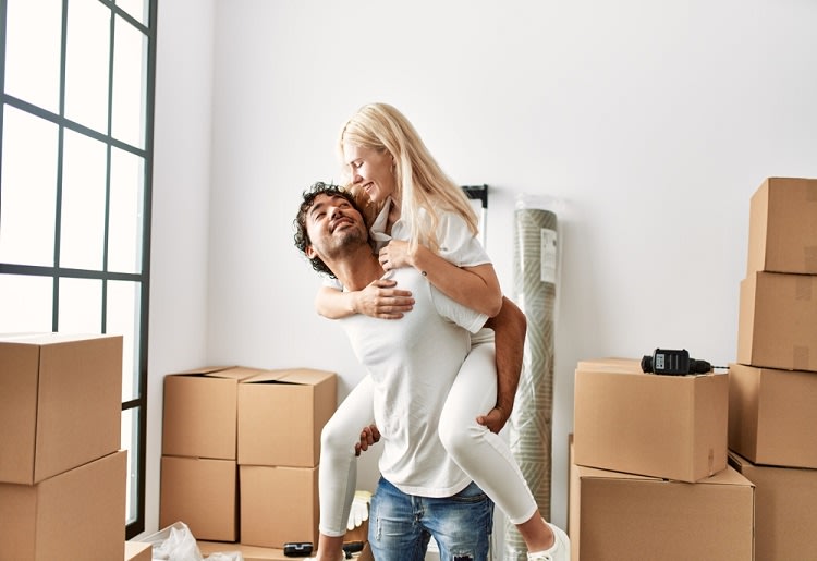 Woman on her partner's back surrounded by boxes