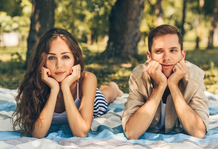 Upset couple lying on a picnic blanket in a park