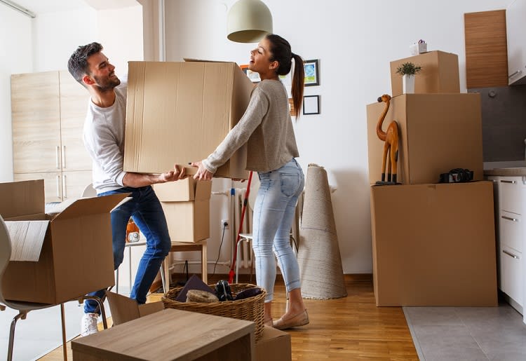 Couple carrying a box together in their new home