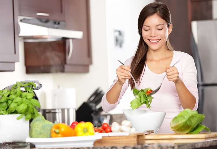 Woman tossing a salad in her kitchen