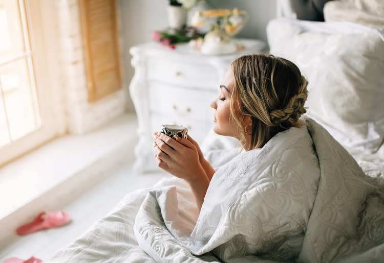Woman in bed waking up with cup of tea