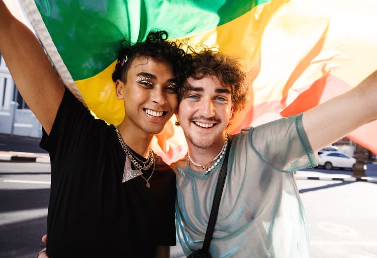 Two queer men holding up pride flag