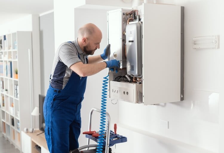 An electrical engineer performing routine maintenance to a water heater.