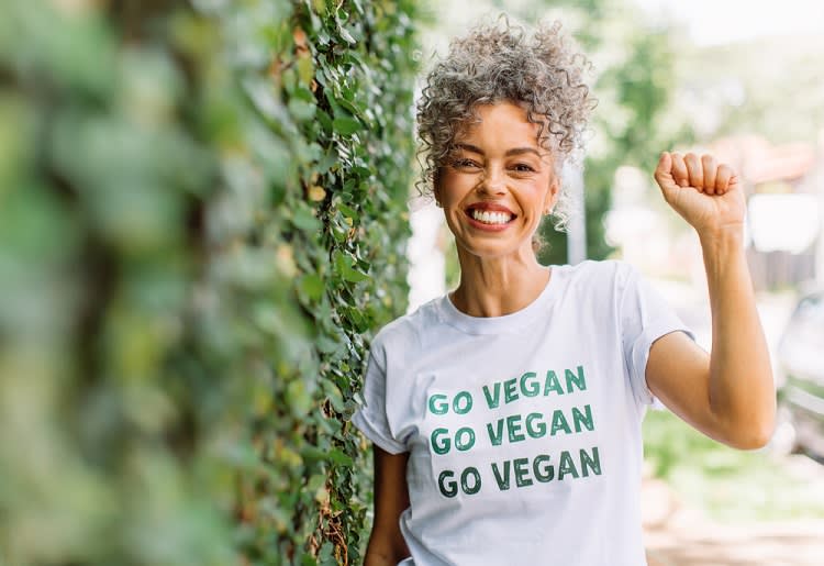 Smiling woman with raised fist and "Go Vegan" shirt