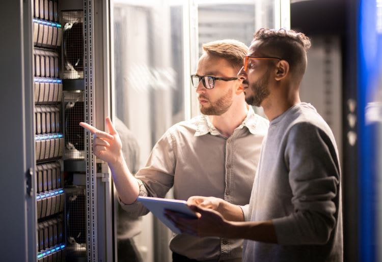 Two IT specialists working in a server room. 