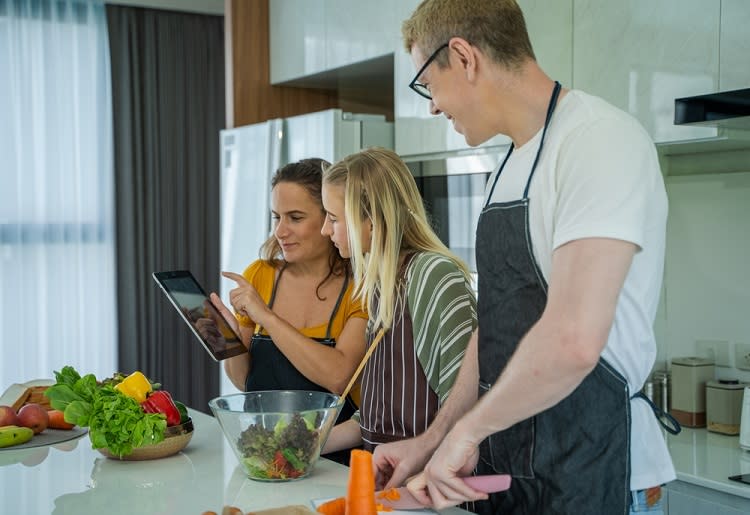 Family cooking together and looking at tablet for instructions