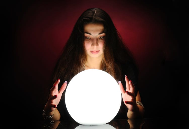 Psychic staring into an illuminated crystal ball.