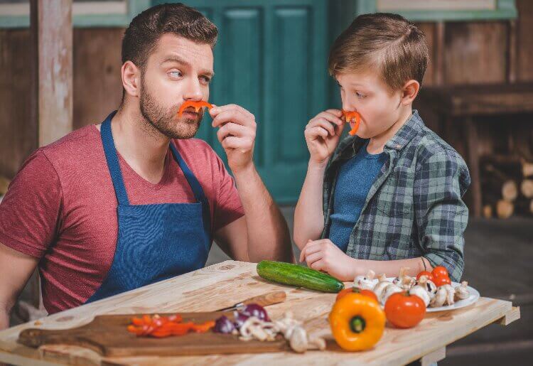 A father and son having fun creating a healthy meal together in the kitchen.