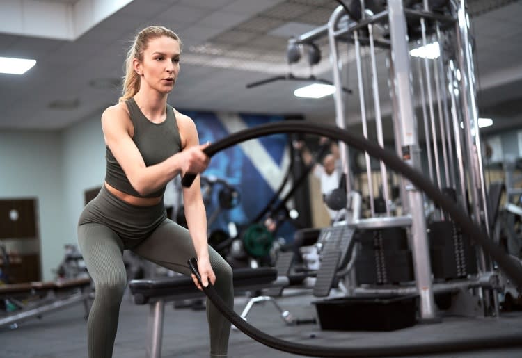 Woman exercising with battle ropes in gym