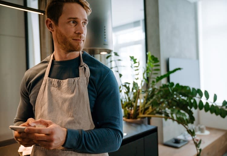 Man in apron using cell phone