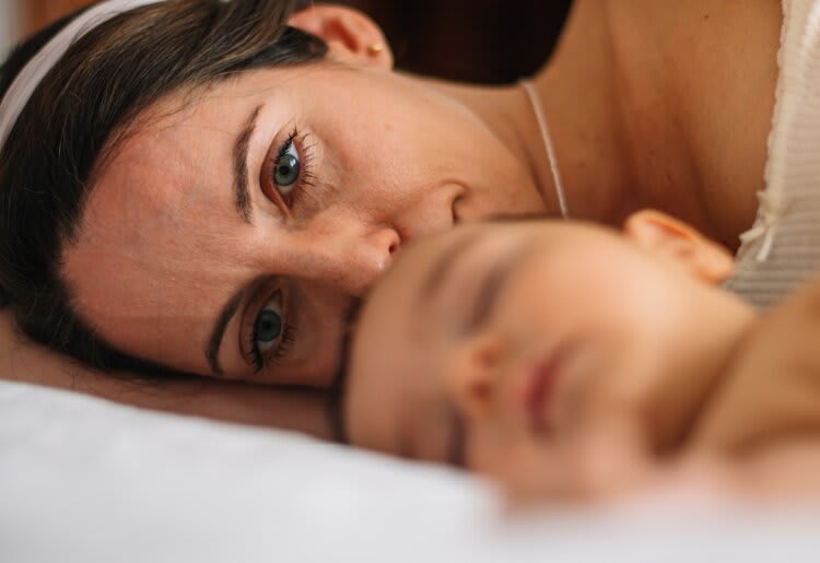 a woman laying on a bed next to a baby