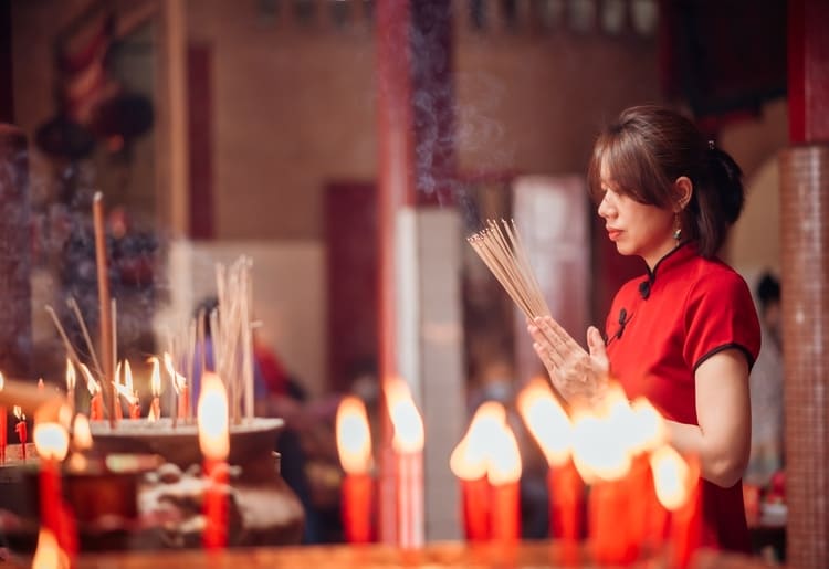 Asian woman lighting incense.