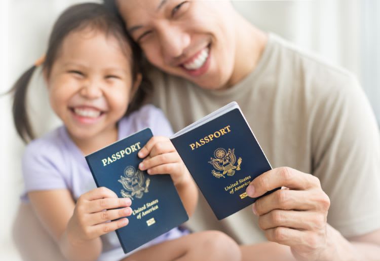 Father and daughter holding American passports with pride, celebrating immigration citizenship.
