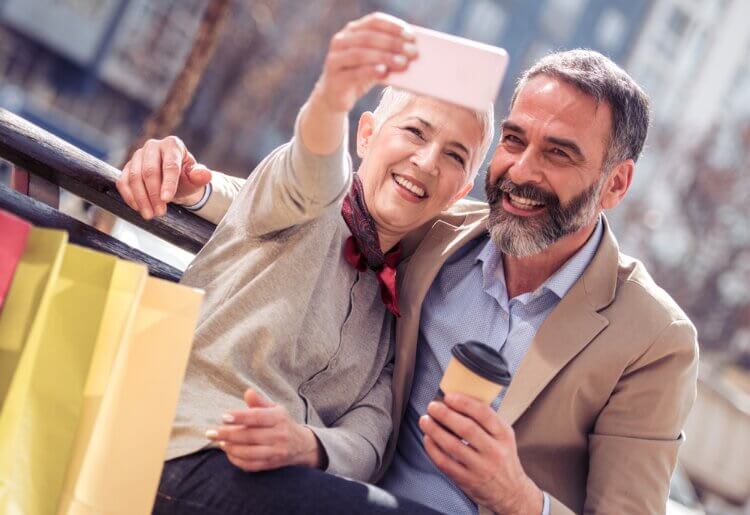 A mature couple having fun taking a selfie with a cell phone.