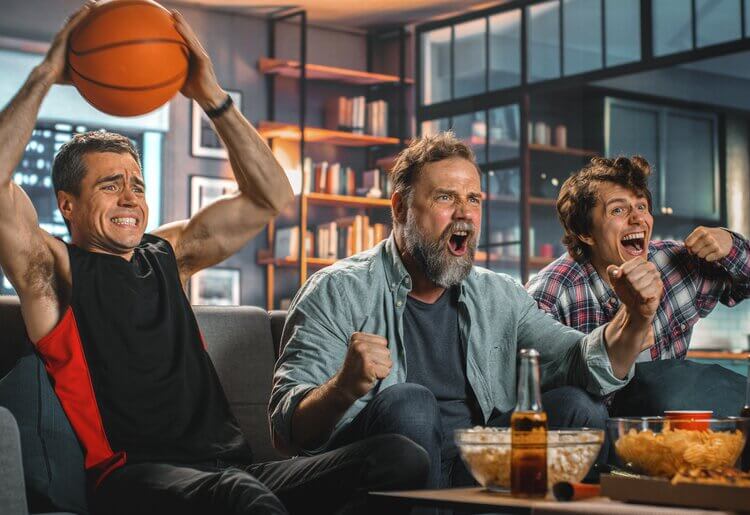 Three men sitting on a couch watching the NBA play-offs.
