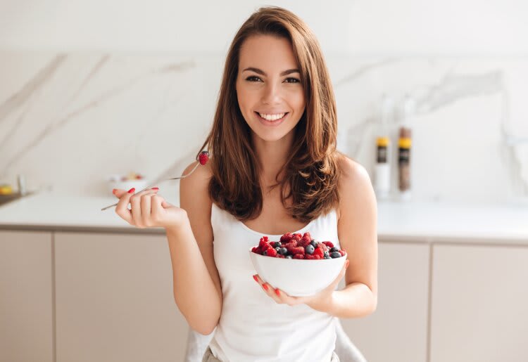 A woman eating a bowl of berries for weight loss. 