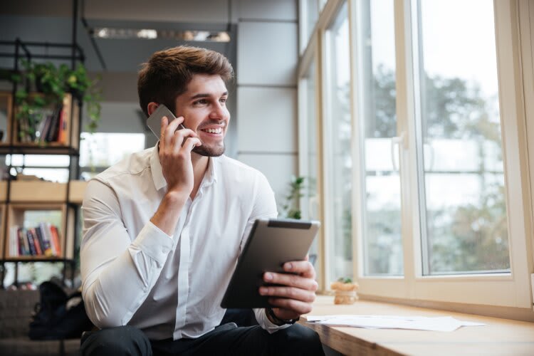 A man talking on his cellphone through his phone carrier. 