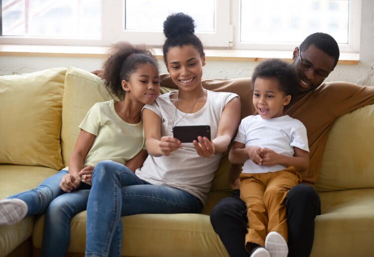 A family sitting on a couch watching a show with their new cell phone plan.