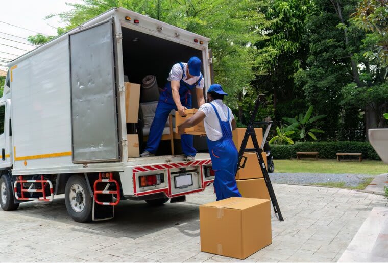Two men from a long distance moving company unloading boxes 