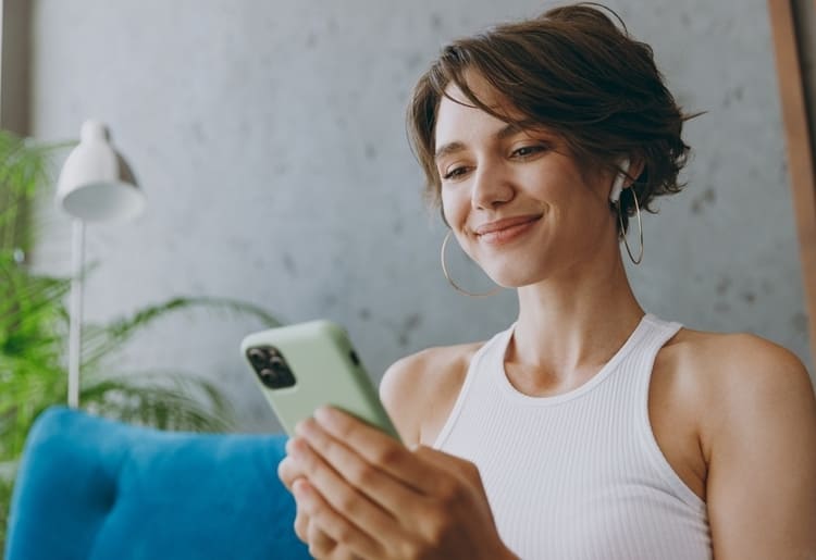 A woman on a couch reviews the benefits of her prepaid phone plan.