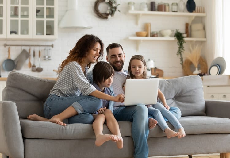 Family sitting on couch looking at laptop