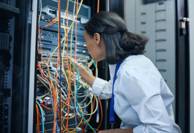 A female IT professional rewiring cables in a server room.
