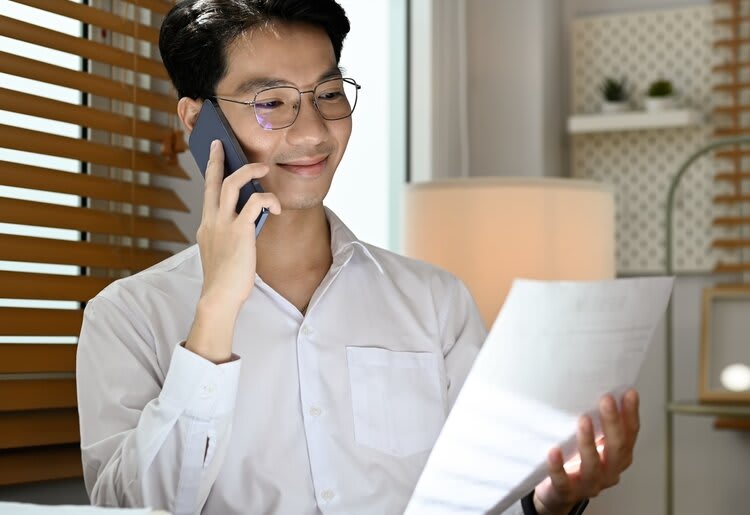 Man looking at a paper document while on the phone.
