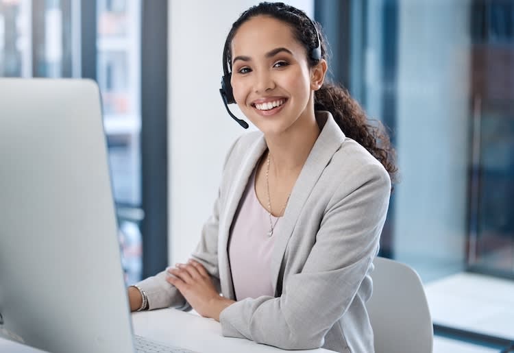 A woman sitting in front of a computer with a VoIP headset.