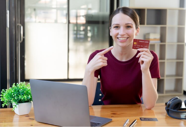 Smiling person pointing at their credit card.