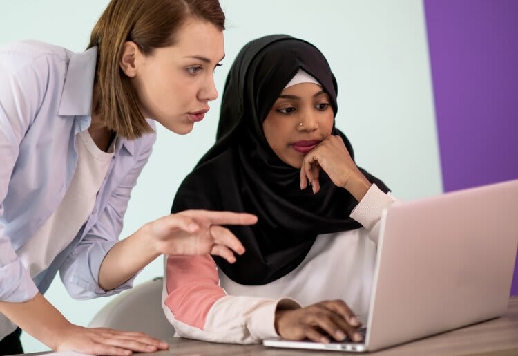 Two woman evaluating something on a laptop.