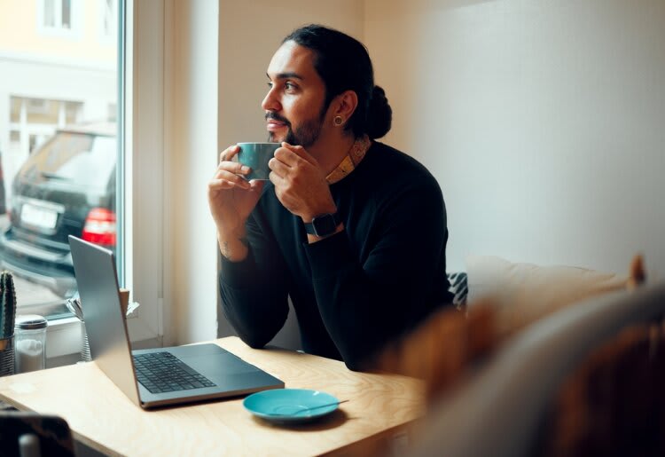 Person drinking coffee in front of a laptop.