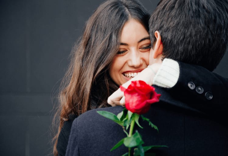 a woman hugging a man with a red rose in her hand