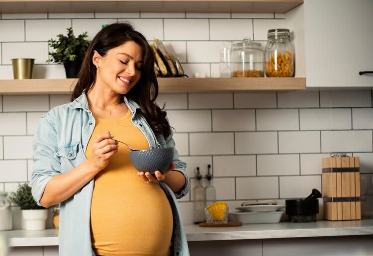 Pregnant woman eating in the kitchen.