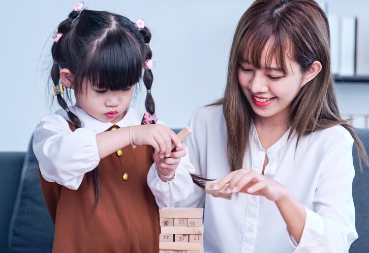 Mother helping small child with building blocks.