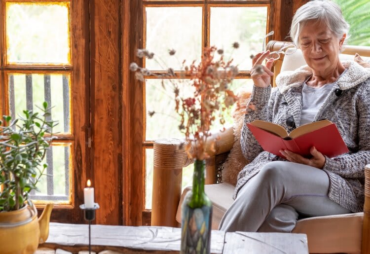 Smiling senior woman that lives alone reading a book.