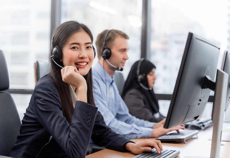A woman in a headset smiling next to her male and female colleagues