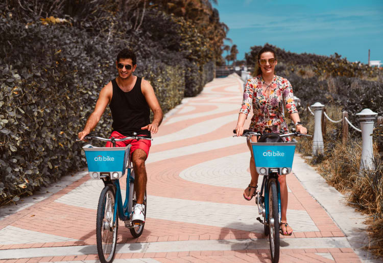 a man and a woman riding bikes down a sidewalk