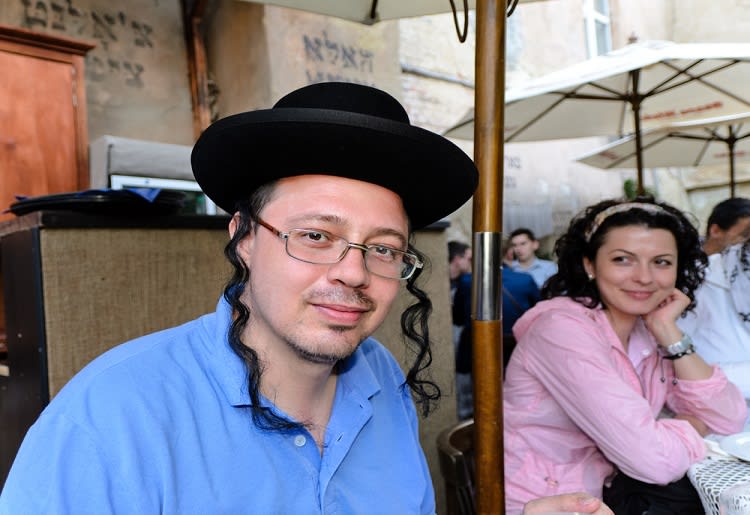 A young orthodox Jew sitting at a table next to a woman 