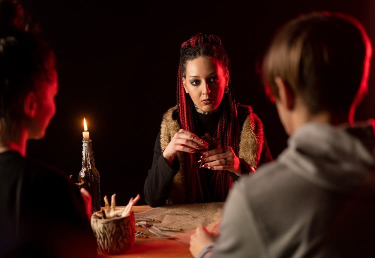 A psychic woman with dreads doing a reading for a young couple