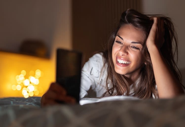 Young brunette woman leaning on her hand smiling at phone 