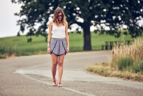 A woman walking alone in the middle of the road in the countryside