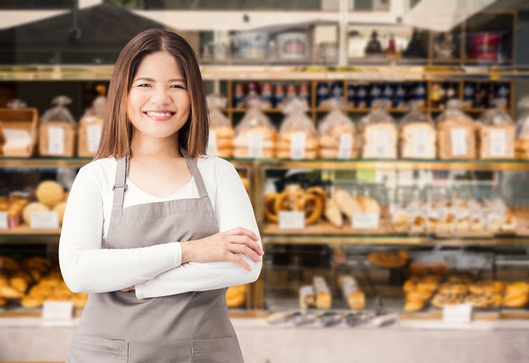 A woman smiles since she chose a Wix template for her bakery website.