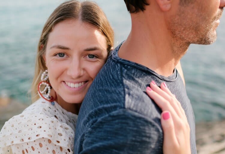 Smiling woman hugging a man from behind.