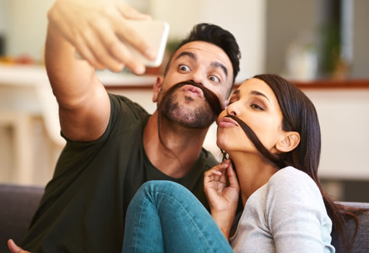 A young couple playfully takes pictures for Movember