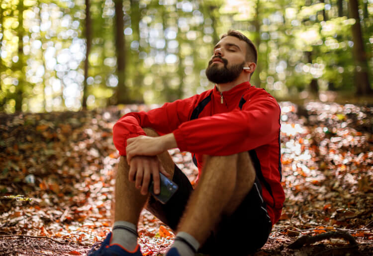 A young man sits in the forest to relax during Sober October