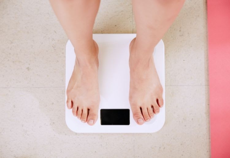 A woman stands on a scale to check her weight