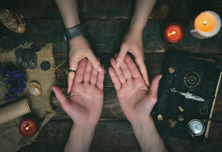 A psychic performs a palm reading on a client.