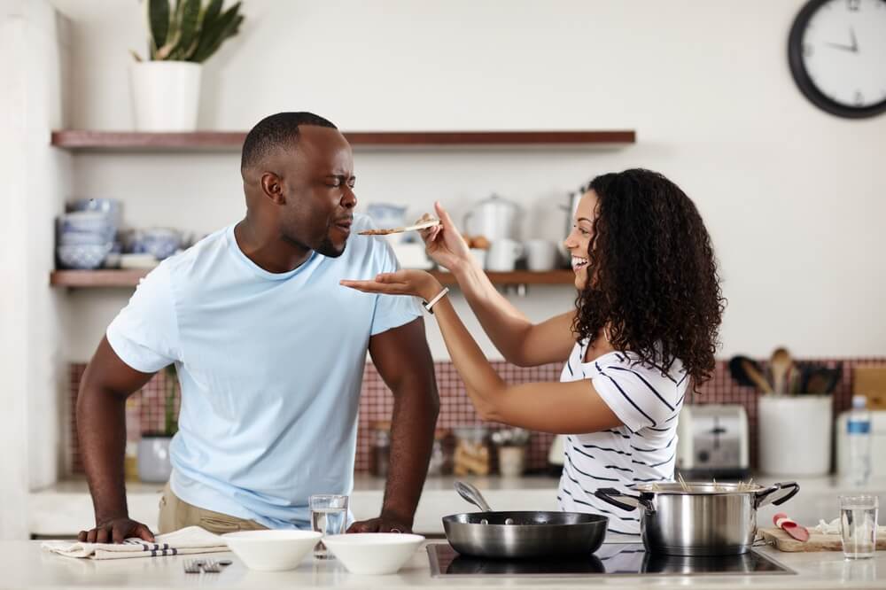 Couple, cooking and kitchen with food taste and eating at home with love, care and feeding. 